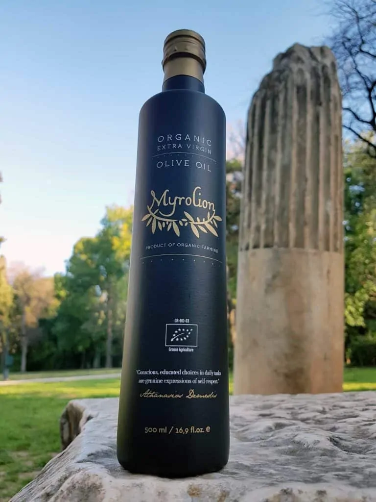 Myrolion Organic Extra Virgin Olive Oil bottle in front of ancient Greek column