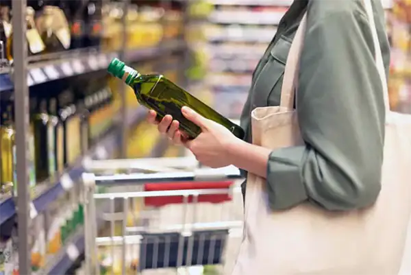 Girl choosing best olive oil in grocery store